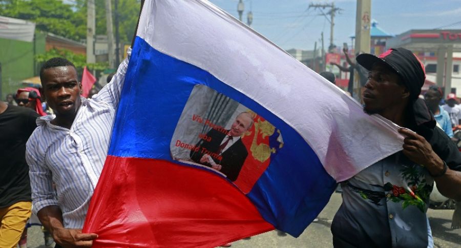 Протестующие жители Гаити несут российские флаги и портреты президента России Путина